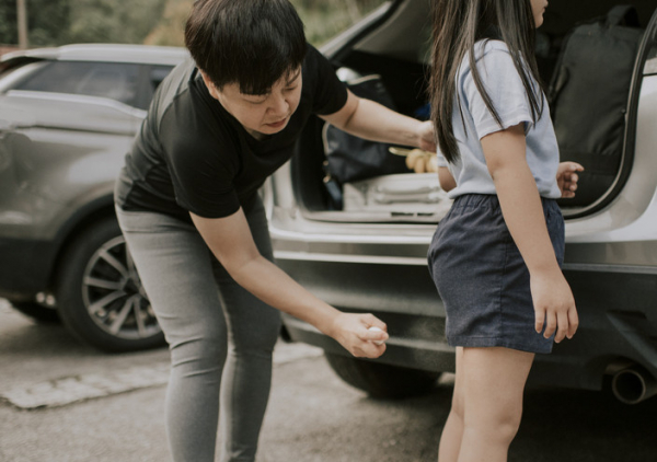 Father spraying the back of his daughter's legs with bug spray